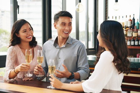 smiling-young-asian-man-two-women-cheering-with-champagne-bar